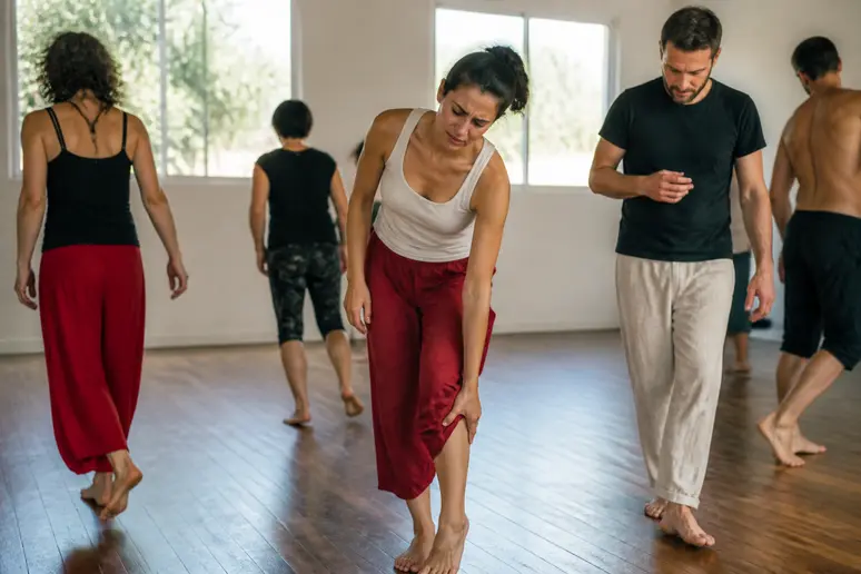 Une pratiquante de Biodanza stoppe son mouvement, attentive à une gêne physique lors de la séance.