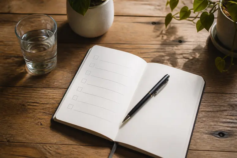 Carnet de notes ouvert sur une table avec une liste de suivi pour les programmes de bien-être