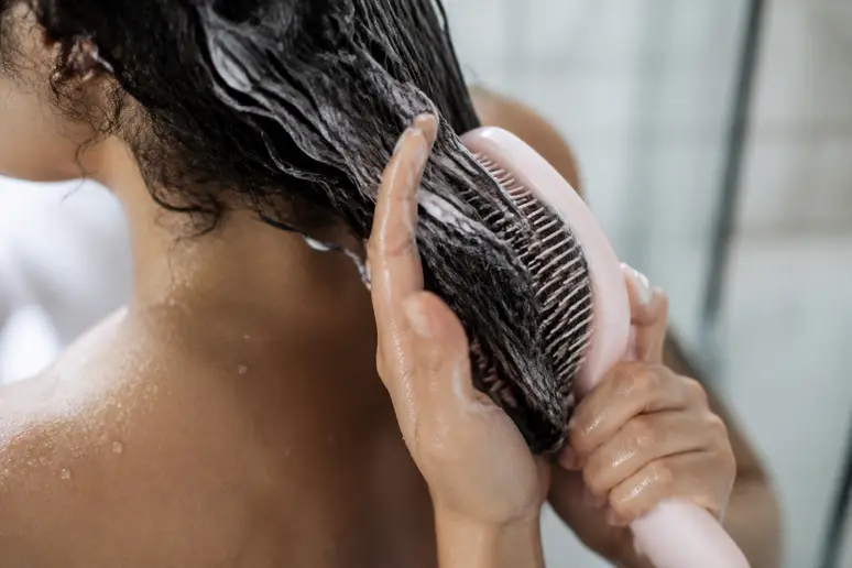 Application d'un soin et démêlage doux sur cheveux bouclés humides avec une brosse adaptée