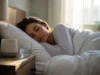 Bruit blanc pour dormir : bienfaits, acouphènes et limites Jeune femme dormant paisiblement près d'un appareil diffusant un bruit blanc pour dormir dans sa chambre