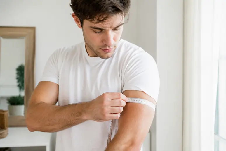 Un homme mesurant sa corpulence avec un ruban souple pour estimer son poids idéal.