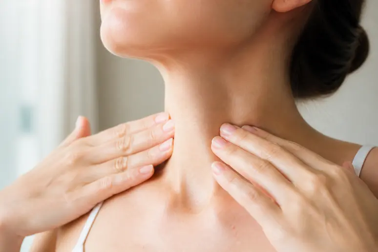 Mains effectuant un drainage lymphatique du visage par une pression légère sur le cou