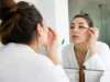 Comment appliquer l’huile de ricin sur les cils sans risque ? Femme appliquant soigneusement de l'huile de ricin cils avec un goupillon propre devant un miroir