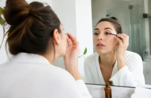Comment appliquer l’huile de ricin sur les cils sans risque ? Femme appliquant soigneusement de l'huile de ricin cils avec un goupillon propre devant un miroir