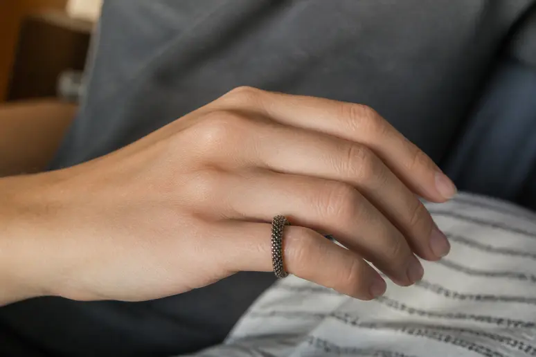Main portant une bague anti ronflement sur l'auriculaire pour illustrer l'acupression digitale