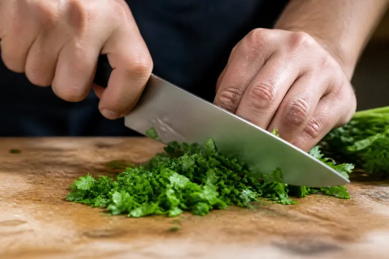 Mains coupant du persil frais sur une planche à découper pour profiter de ses bienfaits