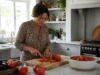 Bienfaits santé de la tomate : cœur, tension et limites Une femme cuisine des tomates fraîches et cuites, illustrant les bienfaits de la tomate pour la santé.