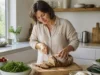 Quel est le meilleur pain pour maigrir sans pic de glycémie ? Femme coupant du pain au levain artisanal sur une planche en bois dans une cuisine lumineuse, idéal pour trouver le meilleur pain pour maigrir.