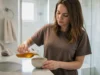 Comment utiliser le vinaigre de cidre sur les cheveux ? Femme préparant son eau de rinçage dans la salle de bain pour savoir comment utiliser vinaigre de cidre cheveux