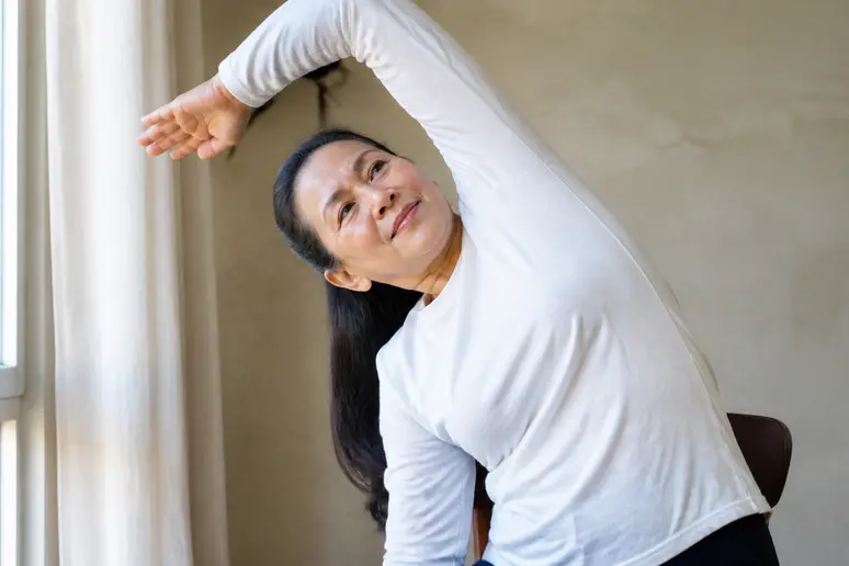 Mains et buste en position d'étirement latéral pour soulager le dos lors d'une séance de yoga sur chaise exercices faciles