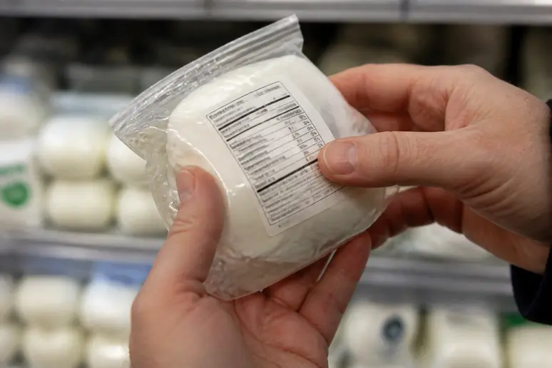 Mains d'une femme enceinte lisant l'étiquette d'une burrata enceinte au lait pasteurisé