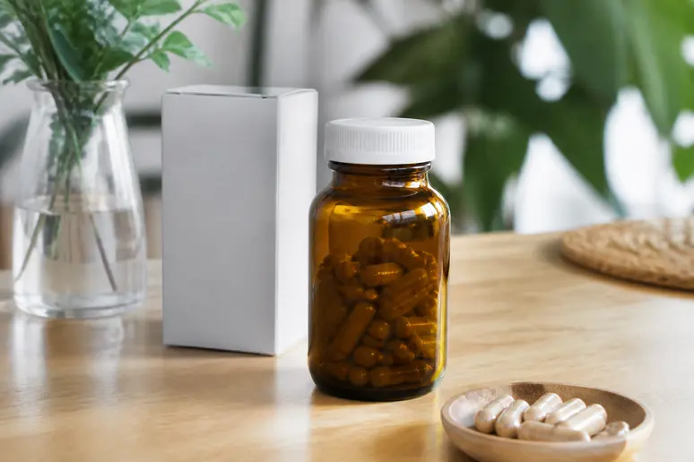 Flacon de gélules et emballage du complément GLP Formula posé sur une table en bois